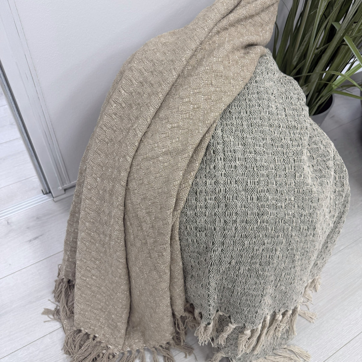 Take A Plaid TAP 2 Armygreen en Beige samen gedrapeerd over jute poef